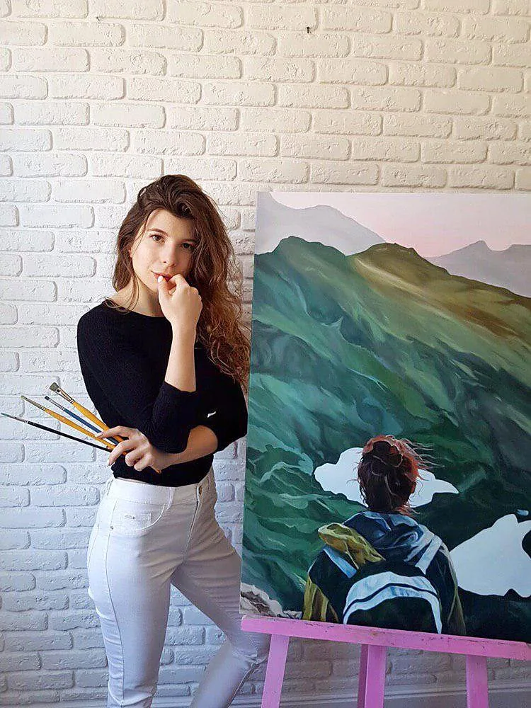 Kate holding brushes next to her large mountain painting